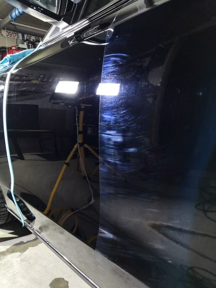 Paint correction in progress — swirl marks being machine-polished out under detailing lights